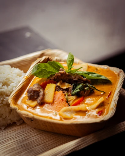 Grön curry med kokosmjölk och grönsaker i takeaway-box med ris